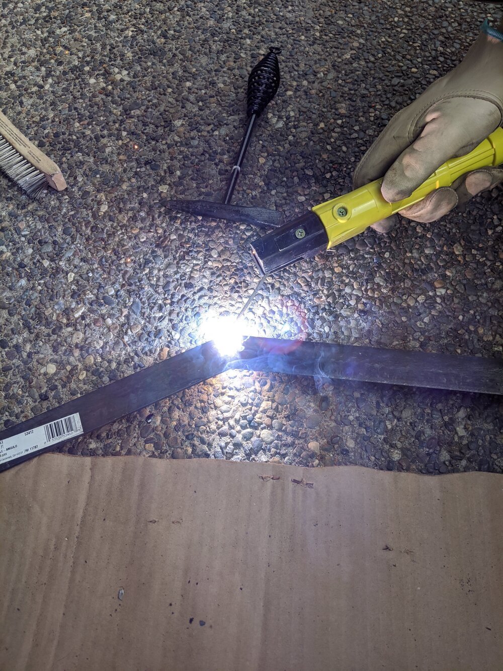 COOL, right?? The trick is to keep your hand steady, and keep the weld stick the right distance away from the metal so you don’t accidentally melt it into a pile of useless goop!  [Photo: arc welding a metal frame]